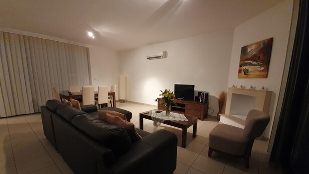 A living room with a sofa, a coffee table, a TV, and a fireplace. - Akamas Seaview Villa Imogine (Neo Chorio)