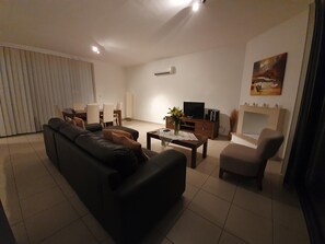 A living room with a sofa, a coffee table, a TV, and a fireplace.