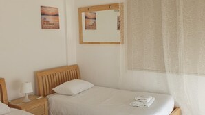 A hotel room with two single beds, a bedside table with a lamp, a mirror, and a view of the sea through sheer curtains. - Akamas Seaview Villa Imogine (Neo Chorio)