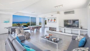 En moderne stue med billardbord, sofaer, sofabord og stort fjernsyn.