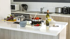 Cocina moderna con encimera blanca, electrodomésticos de acero inoxidable y ventana con vistas al verdor.