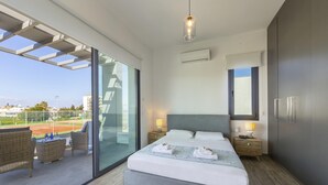Un dormitorio moderno con una cama grande, dos mesitas de noche, un ventanal y vistas a una cancha de tenis.