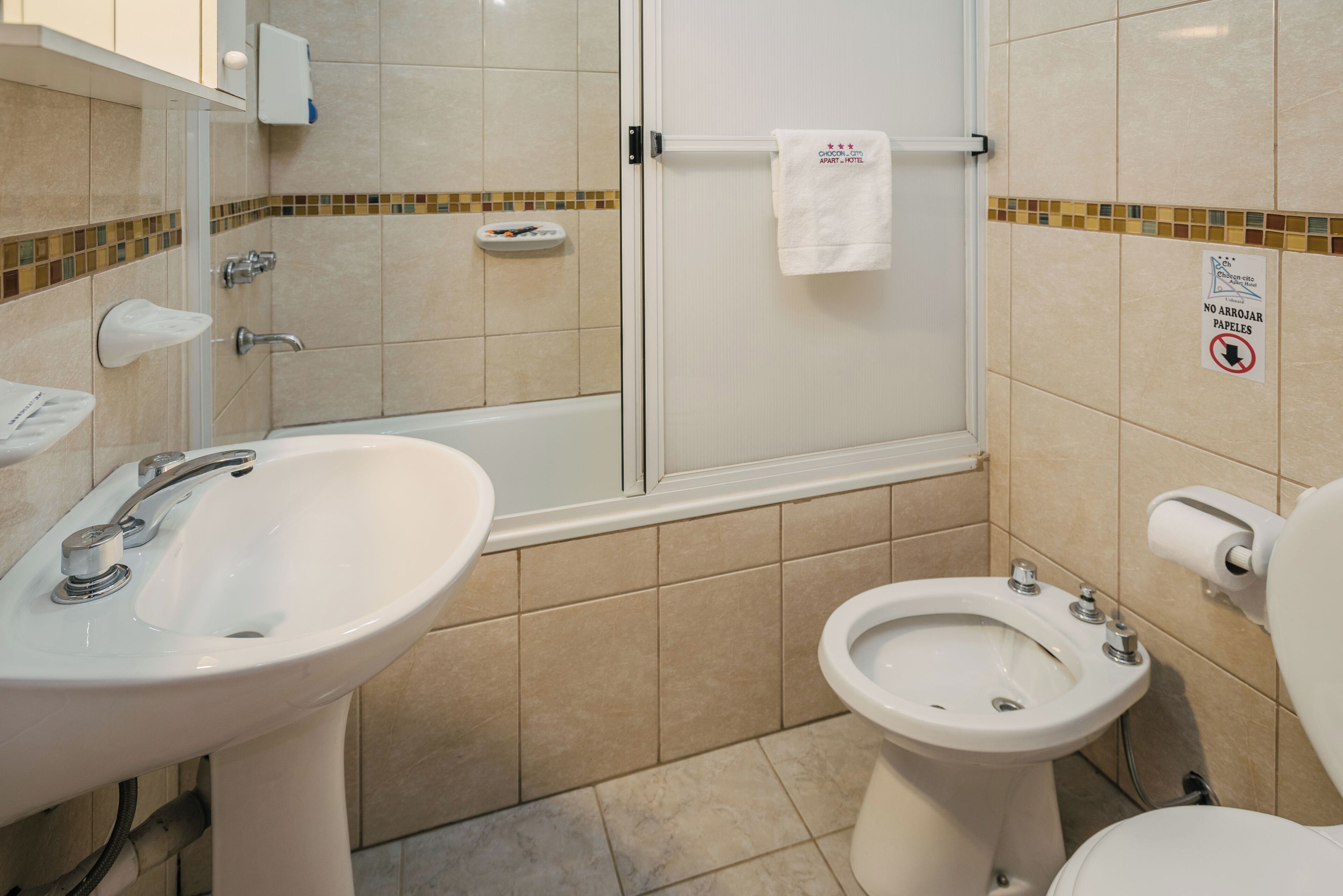 A bathroom with a sink, bidet, toilet, and glass shower enclosure.