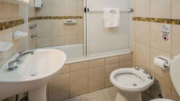 A bathroom with a sink, bidet, toilet, and glass shower enclosure.