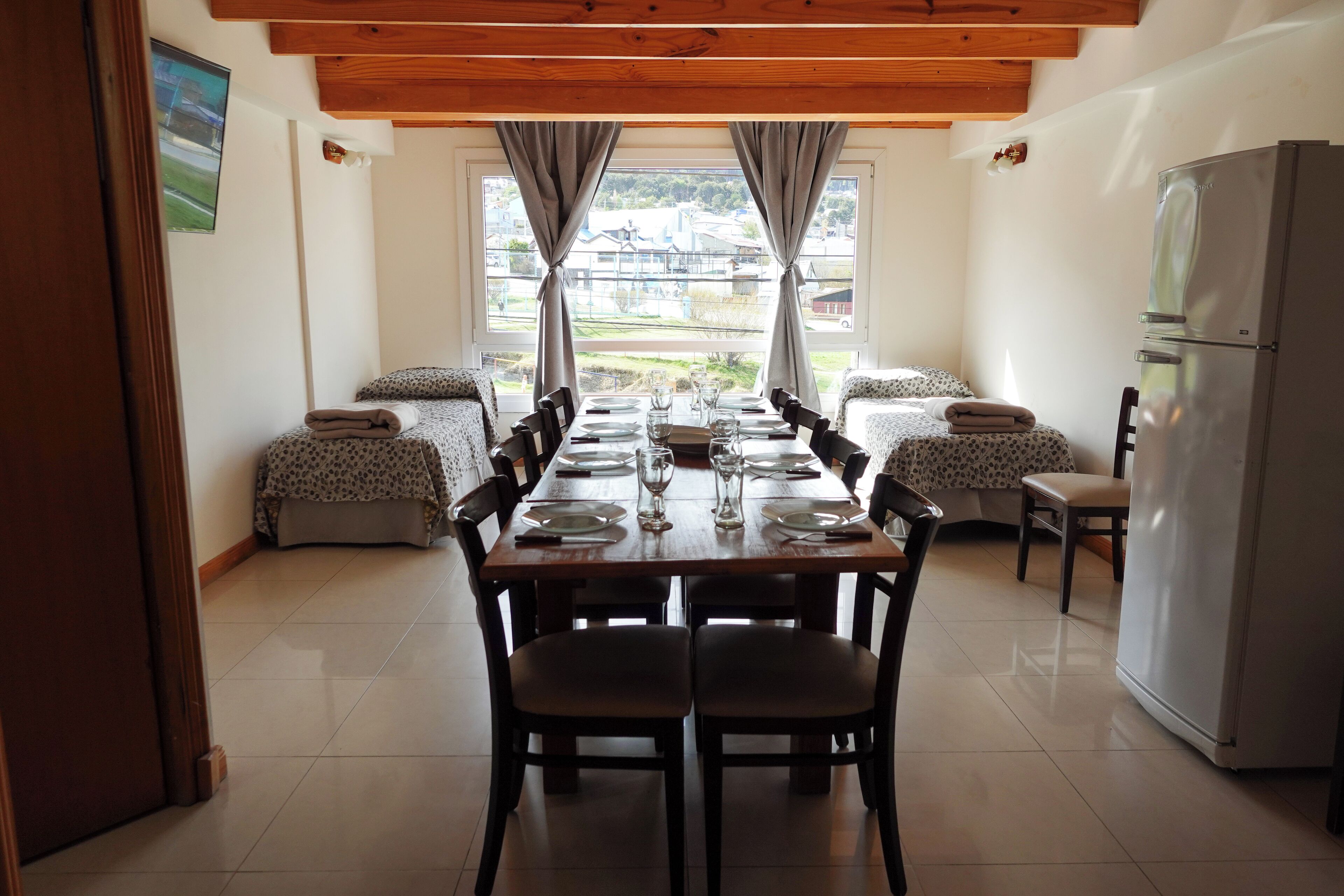 Un comedor con una mesa de madera preparada para cuatro personas, flanqueada por dos sofás estampados.