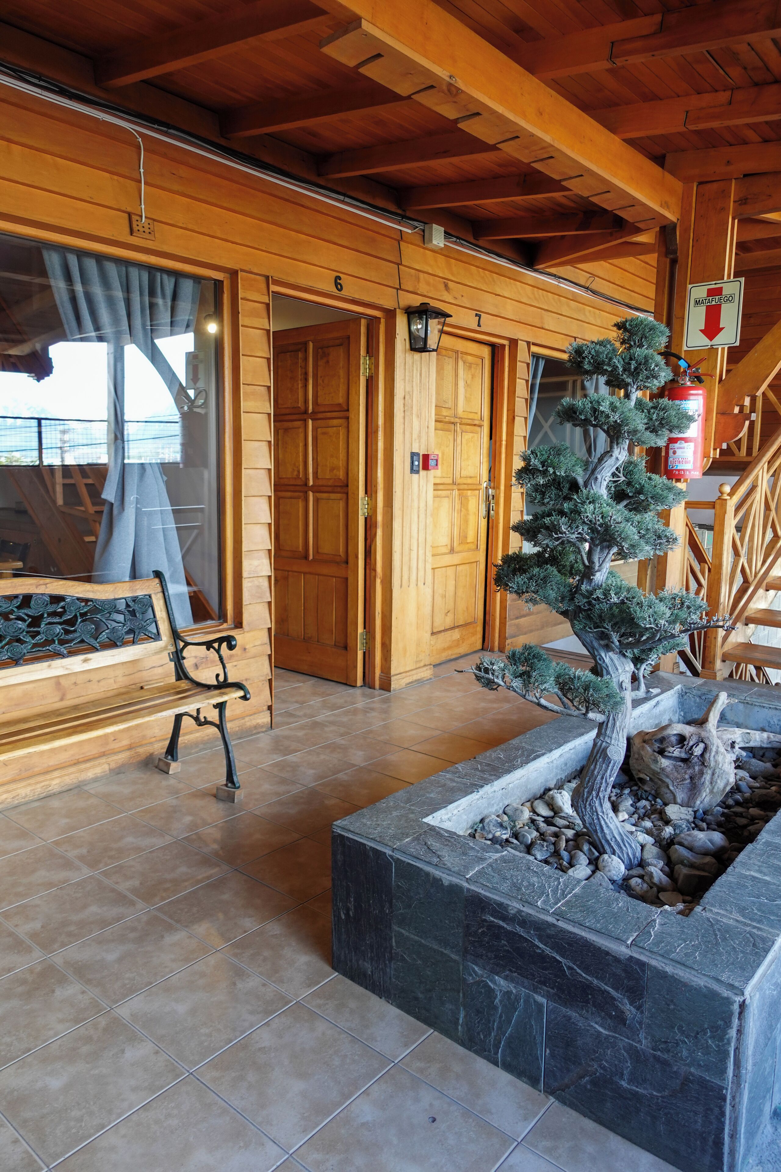 A wooden interior with a bench, a potted tree, and a stone planter.