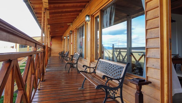 A wooden deck with benches and large windows overlooking a scenic view.