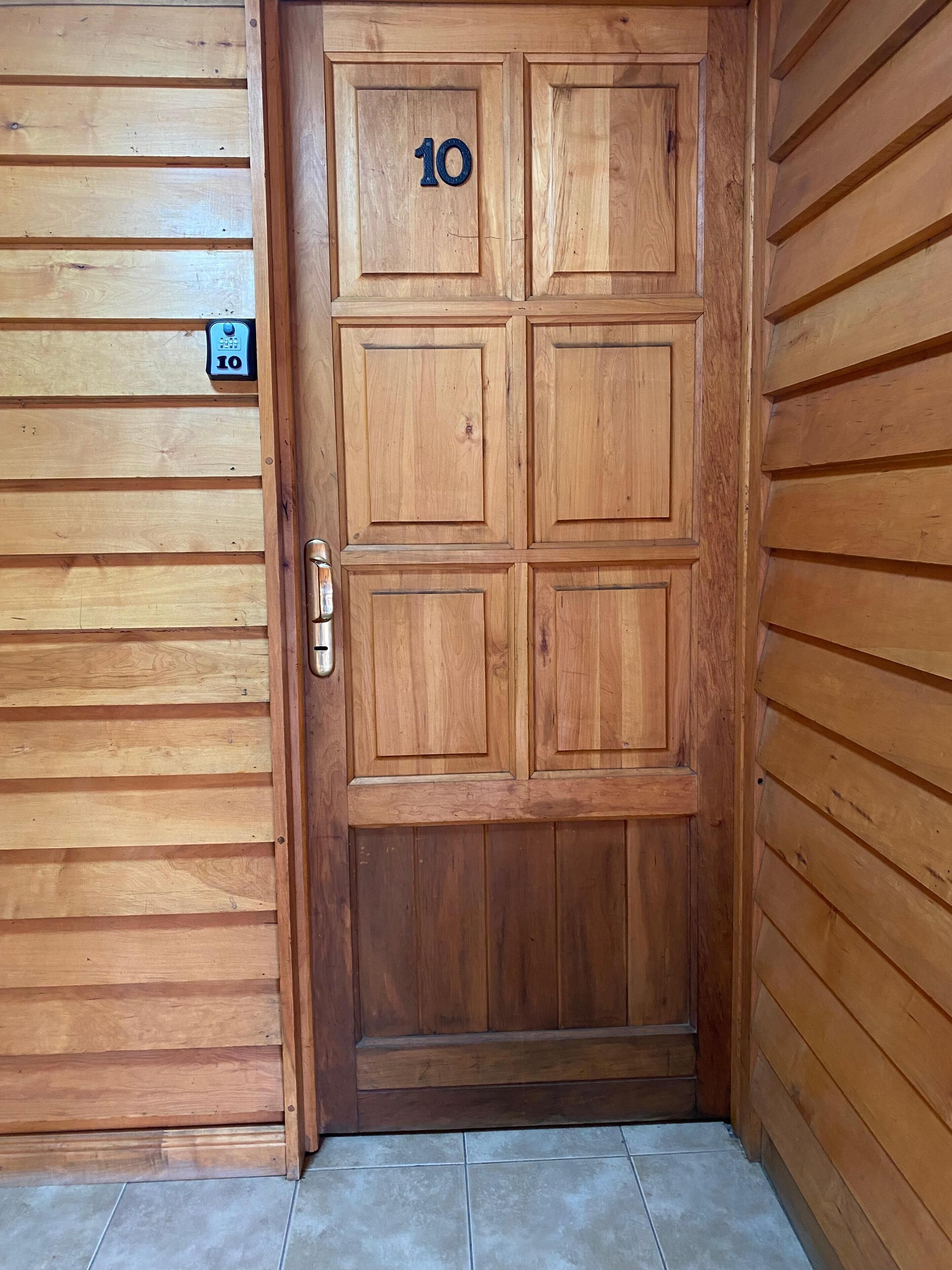 A wooden door with the number 10, a metal handle, and a small sign above it.