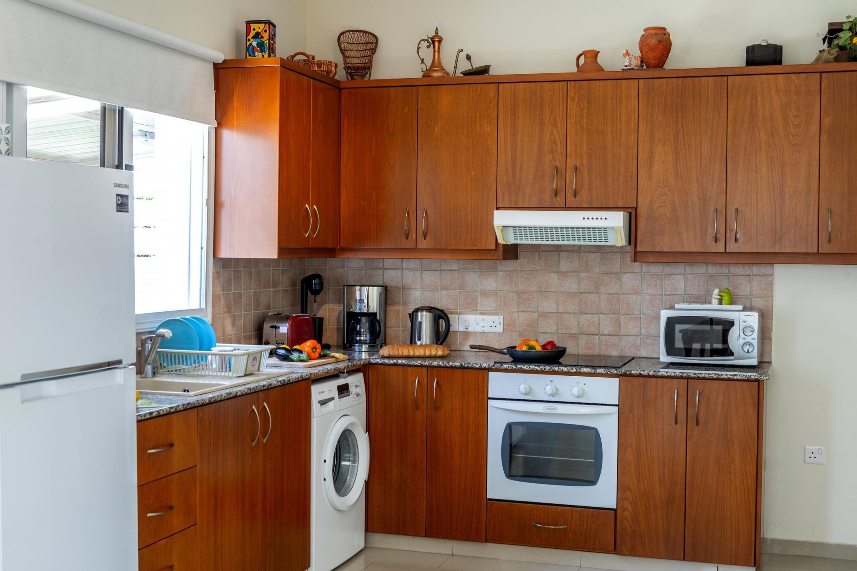 Una cocina con armarios de madera, lavadora, microondas y estufa.