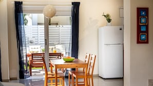 A dining area with a wooden table and chairs, a white refrigerator, and a decorative wall piece. - Galleria Sunset Villa (Paralimni)