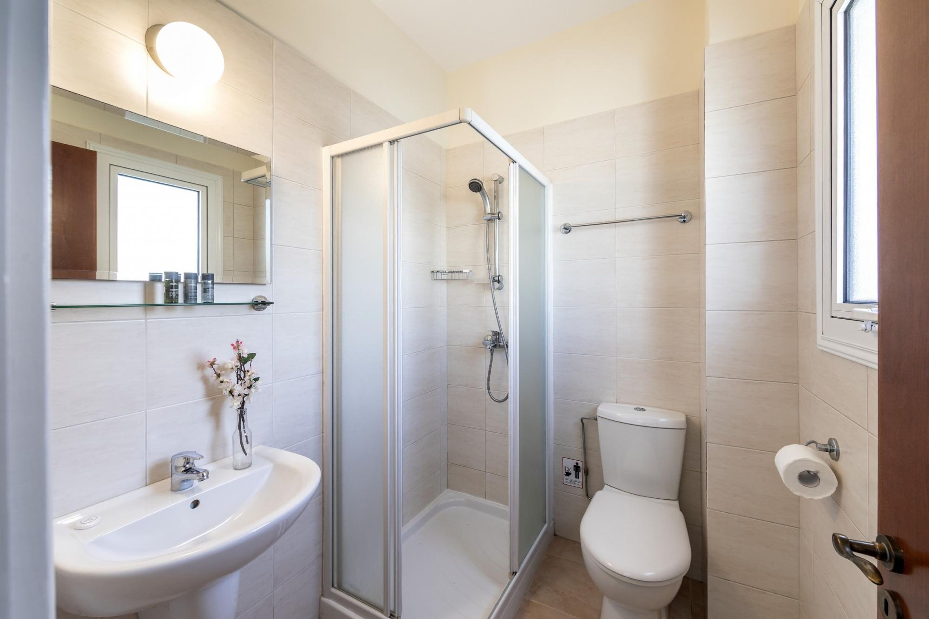 Un baño moderno con ducha de mampara de vidrio, un lavabo blanco y un inodoro.