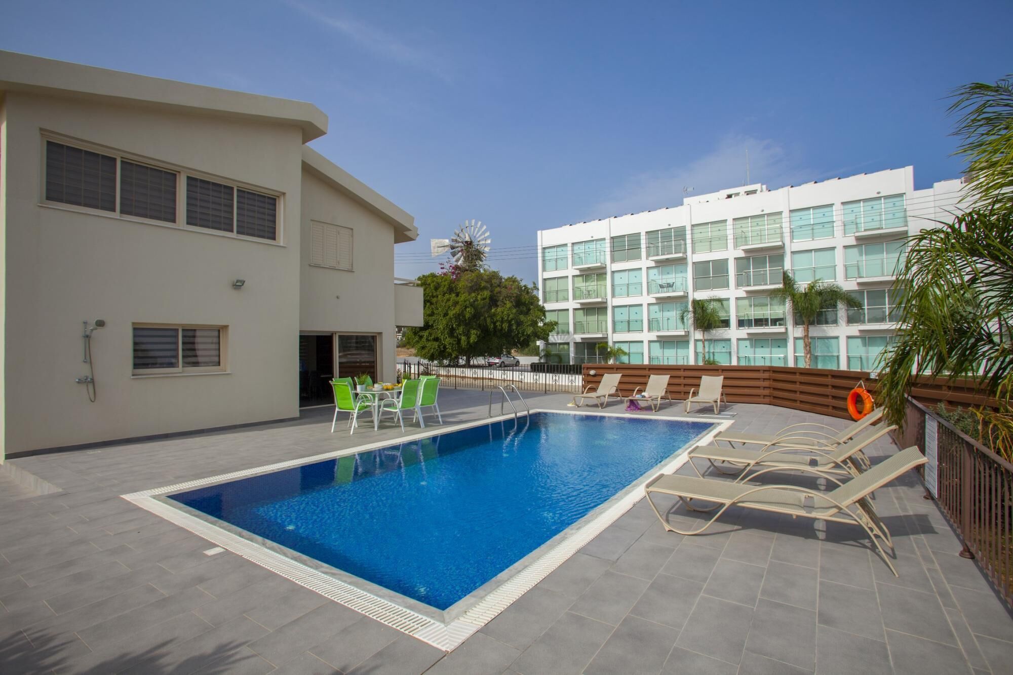 A swimming pool with lounge chairs and a building in the background.