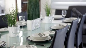 Ein Esszimmertisch mit Tellern, Gläsern und Besteck, umgeben von Stühlen.