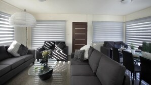A modern living room with a sofa, armchairs, a coffee table, and a dining area with a table and chairs. - Theodora 16 in Protaras (Paralimni)