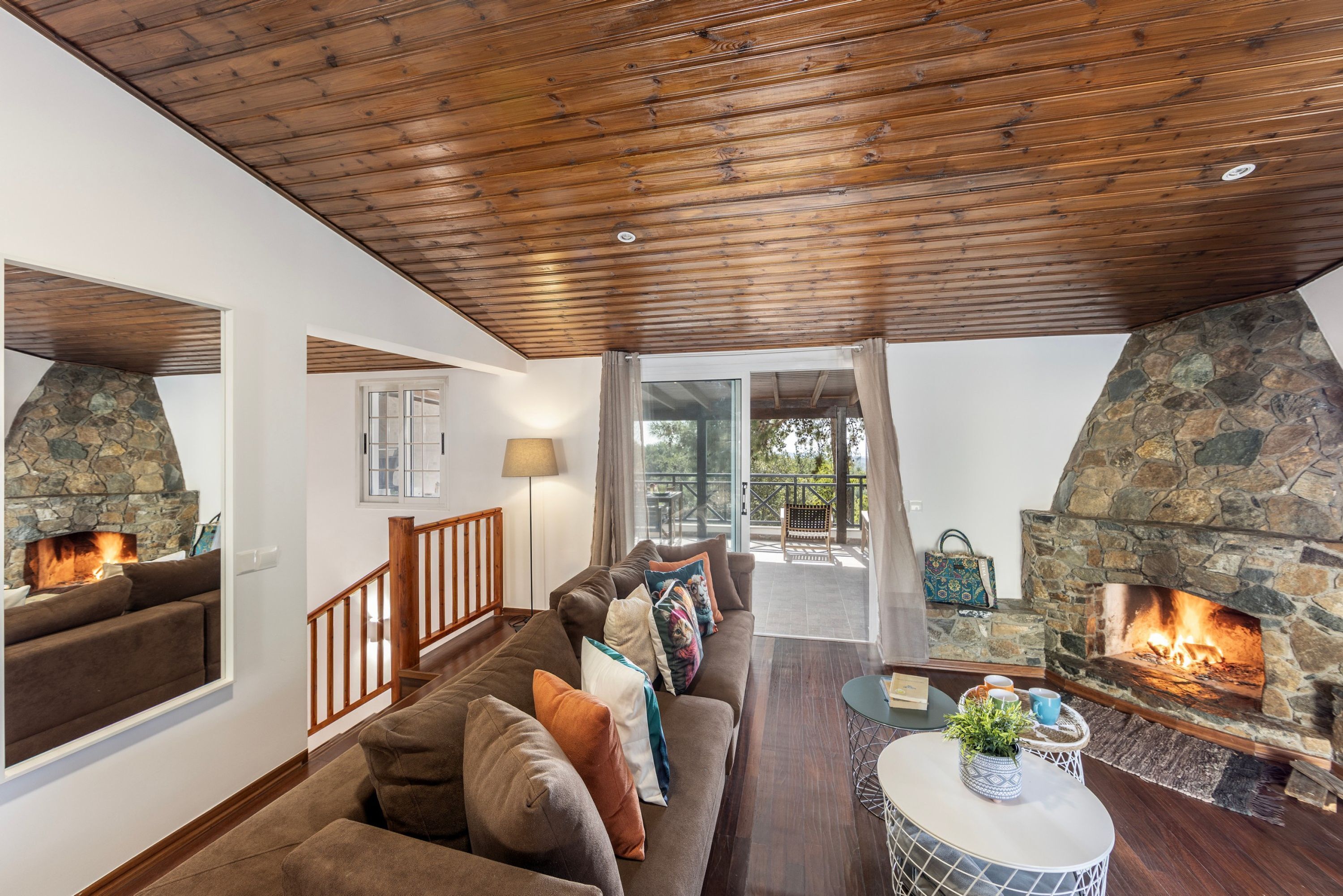 Un salon chaleureux avec une cheminée en pierre, un plafond en bois et un canapé confortable.