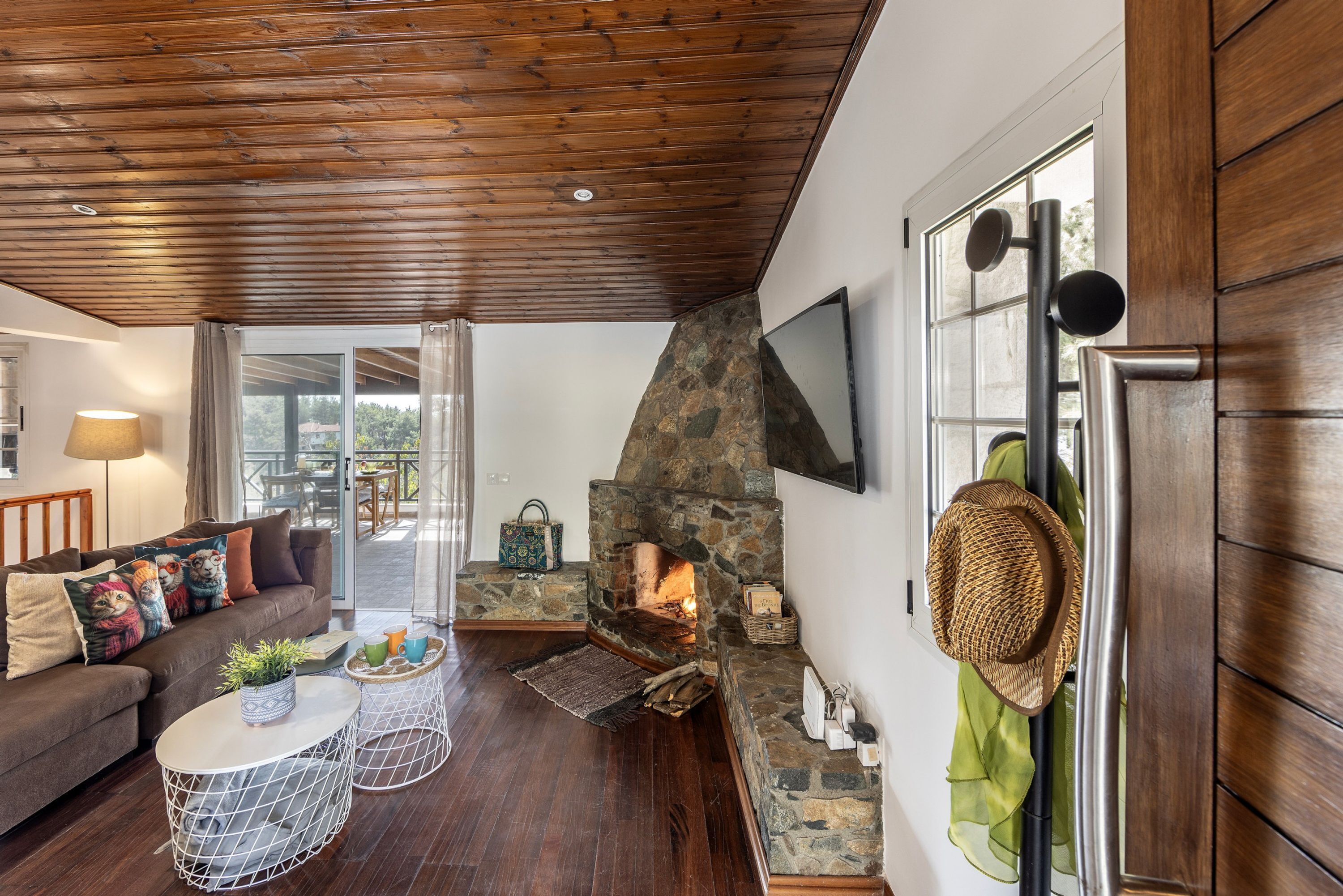 A cozy living room with a stone fireplace, wooden ceiling, and a comfortable sofa.