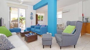 Un salon avec un mur d’accent bleu, un fauteuil gris et un canapé blanc.