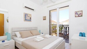Une chambre à coucher comprenant un lit, des tables de chevet, une armoire et un balcon avec une table et des chaises.