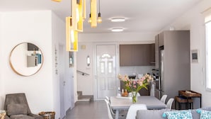 A modern living room with a grey sofa, a round mirror, and a dining area with a table and chairs. - Ayia Thekla Seafront Villa Dagi (Sotira)