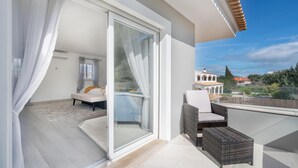Een balkon met een bank, een rieten stoel en een bijzettafeltje.