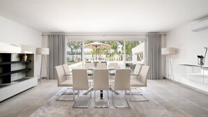 Een moderne eethoek met een glazen tafel, witte stoelen en uitzicht op het buitengebied.