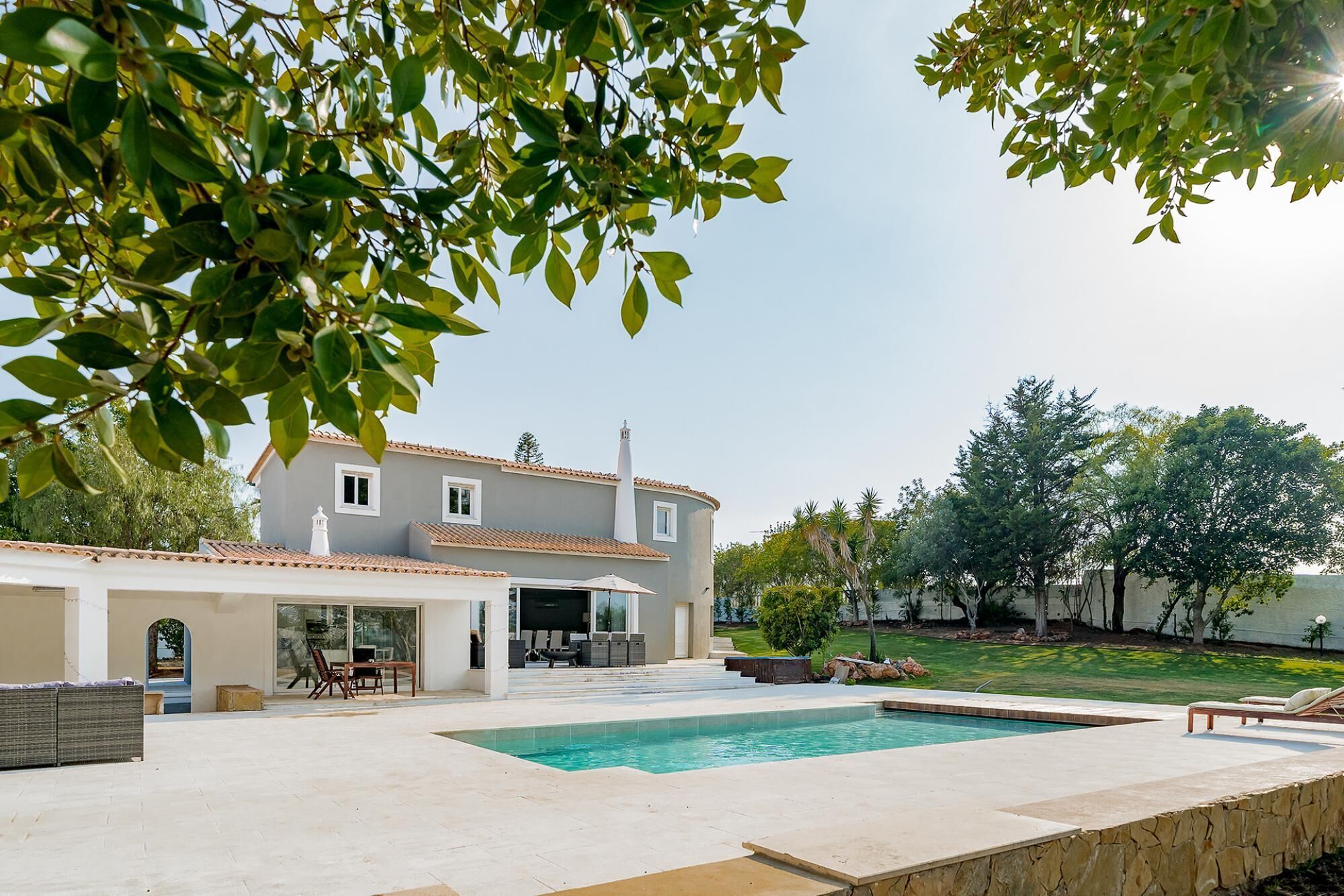Une maison moderne dotée d’une piscine, d’un espace salon extérieur et d’un jardin.