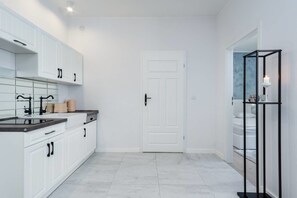 Kitchen features white cabinetry, a black countertop, and a black shelf unit.