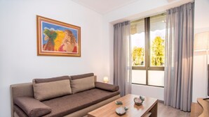 A modern living room with a sofa, a coffee table, and a painting on the wall. - Cozy Glyfada Getaway 1 bdr (Glyfada)
