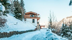 Un chalet moderne avec une façade en bois, un balcon et un mur en pierre.