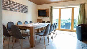 Ein Essbereich mit Holztisch und -stühlen, einem an der Wand montierten Fernseher und Blick durch große Schiebeglastüren.