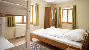 Ein Schlafzimmer mit einem Etagenbett, einem Holzschrank und einem Bett mit weißer Bettwäsche.
