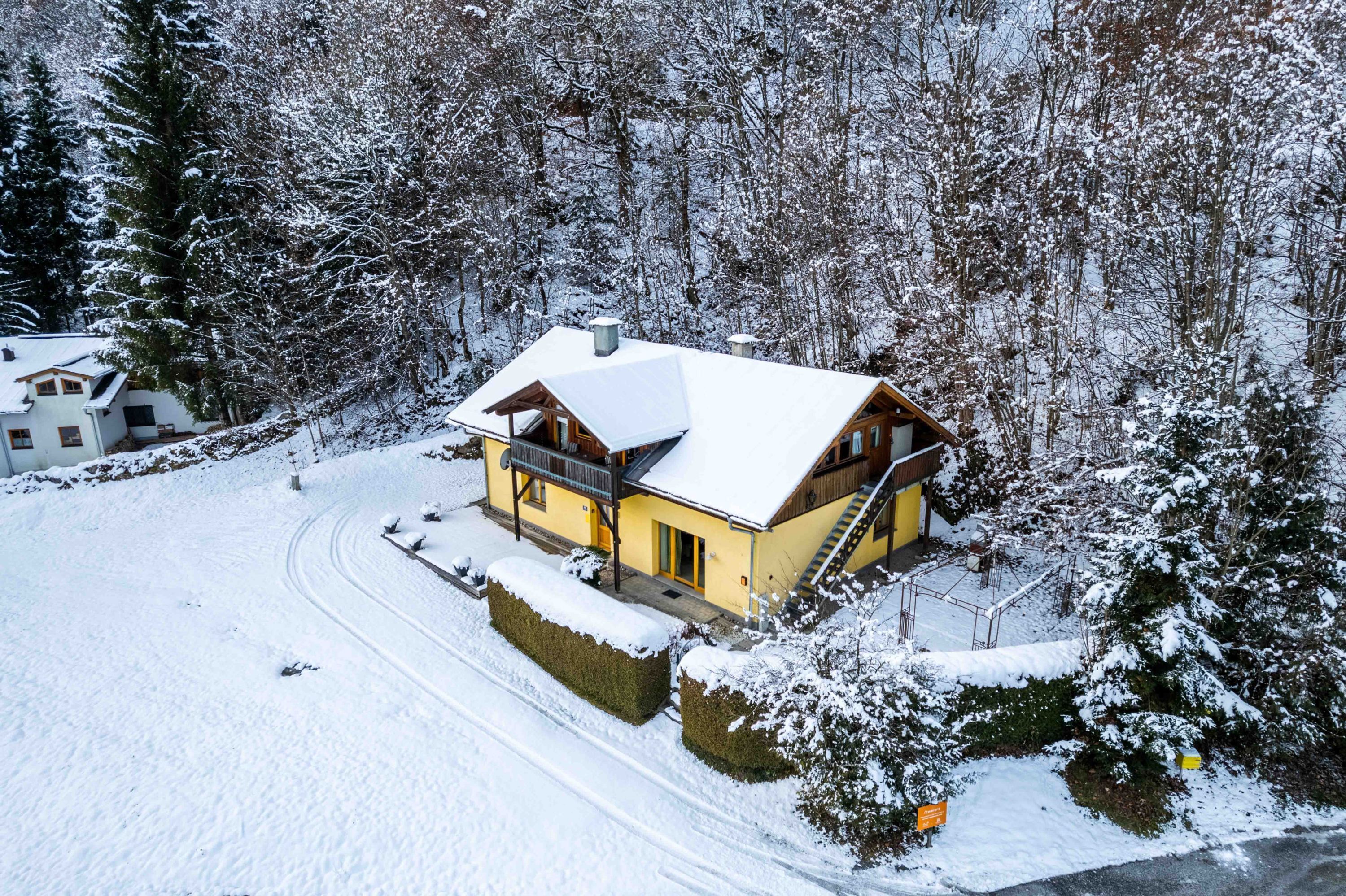A snow-covered lodge with a wooden exterior, a balcony, and a snow-covered roof.