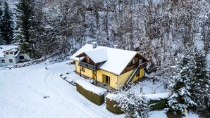 Eine schneebedeckte Holzhütte mit Balkon und verschneietem Dach.