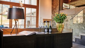 A reception desk with a lamp, wine glasses, and a vase of flowers. - Chalet Evi in Kaprun (Kaprun)
