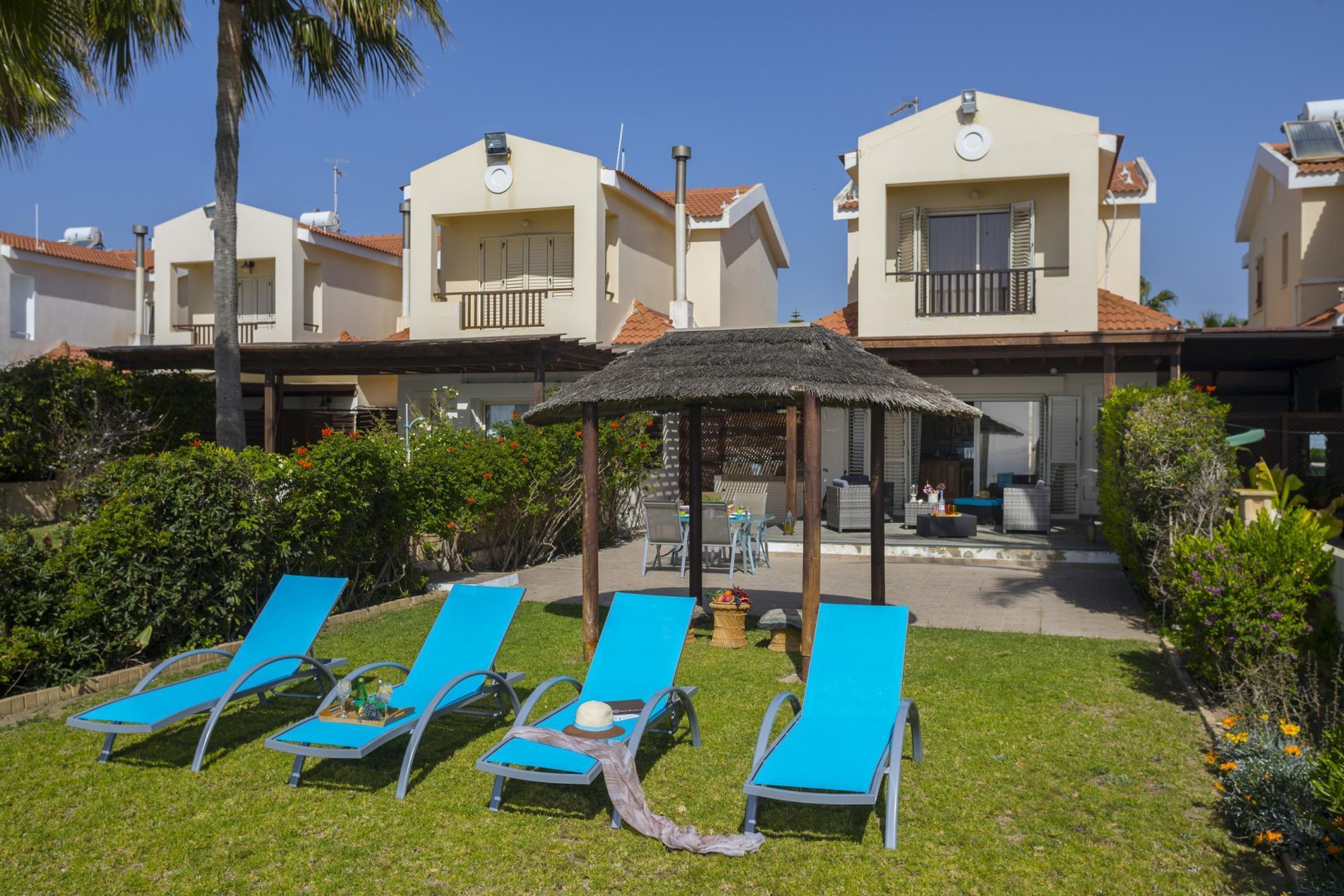 Een resort met meerdere meerlaags gebouwen, buitenzitplaatsen en een rieten parasol.