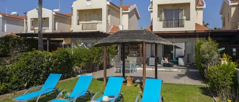 Een resort met meerdere meerlaags gebouwen, buitenzitplaatsen en een rieten parasol.