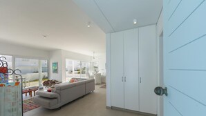 A spacious living room with a large grey sofa, a dining area with a table and chairs, and a white wardrobe. - Protaras Villa Oceania (Paralimni)