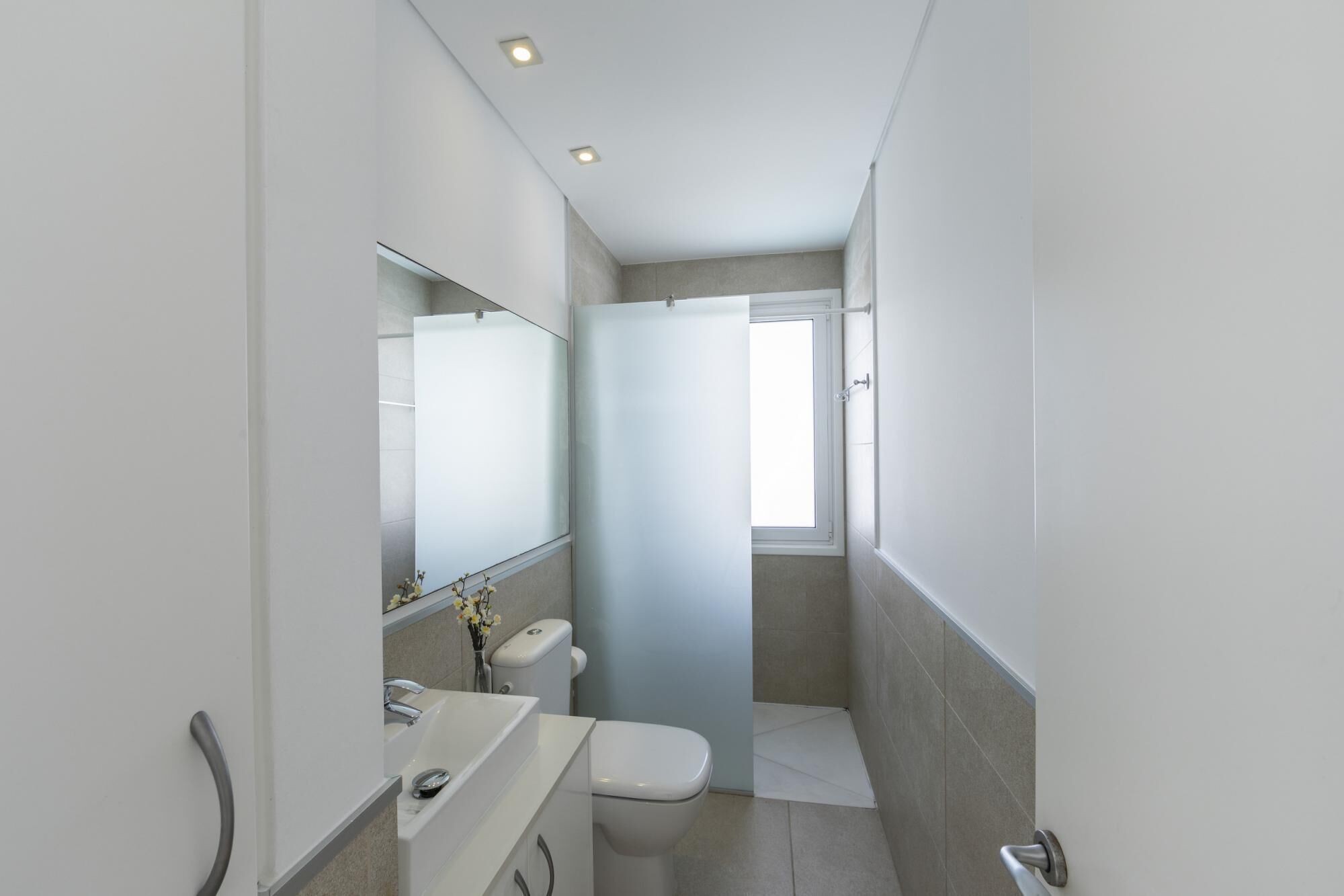 A modern bathroom with a toilet, sink, and mirror.