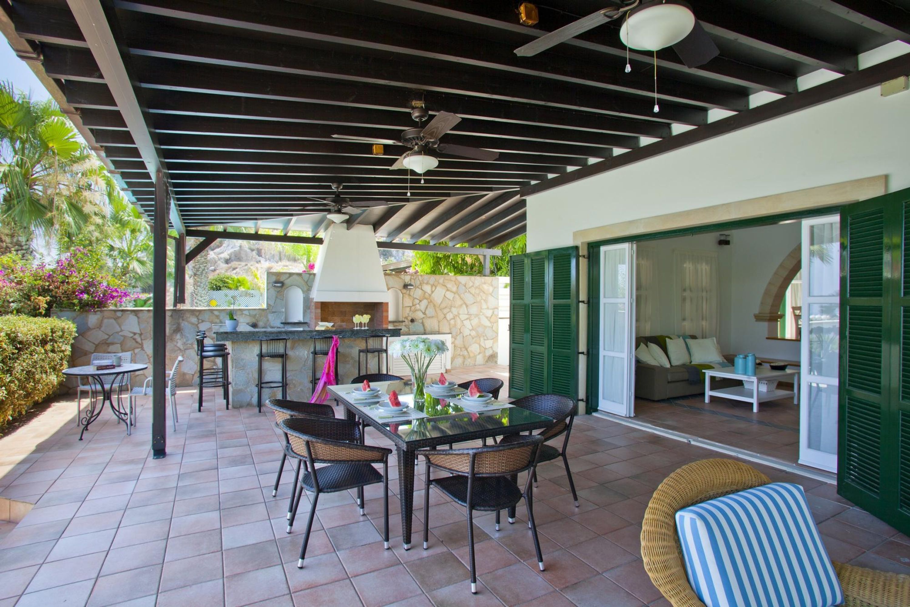 An outdoor patio with a dining table and chairs, a grill, and a seating area with a sofa and a coffee table.