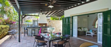 An outdoor patio with a dining table and chairs, a grill, and a seating area with a sofa and a coffee table.