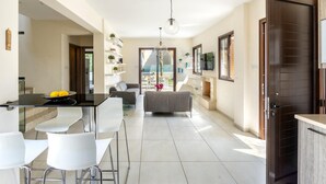 A modern interior with a dining area, a sofa, and a TV. - Ayia Napa Ionion Seaside Villa (Sotira)