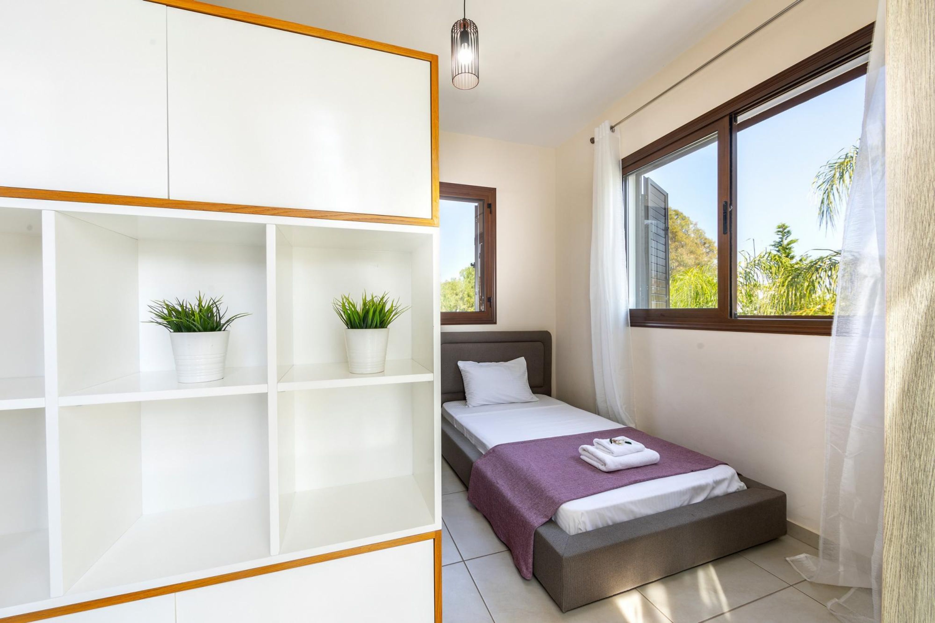 A bedroom with a bed, a wardrobe, a window with a view, and a ceiling light.