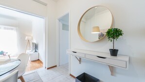 A modern room with a white console table, a round mirror, and a potted plant. - Cozy and Fresh 2bdrm apt Close to Metro (Athens)