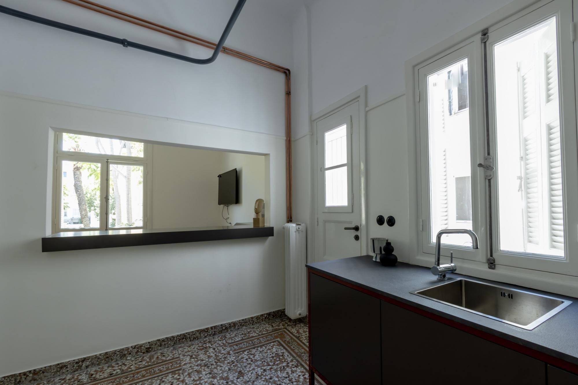 Una cocina con un lavamanos empotrado, una ventana y un radiador.