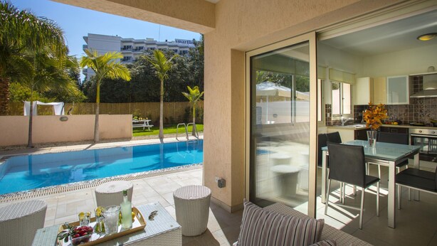 Un appartement moderne doté d’une piscine, d’un coin repas et d’une cuisine.