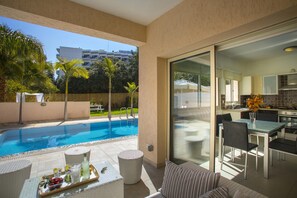 Un apartament modern amb piscina, zona de menjador i cuina.
