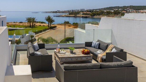 A rooftop terrace with a sofa set, a coffee table, and a view of the sea and landscape. - Protaras Villa Kalena (Paralimni)