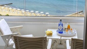 A balcony with a table set for two, featuring a bottle of Cittadella water, snacks, and glasses.
