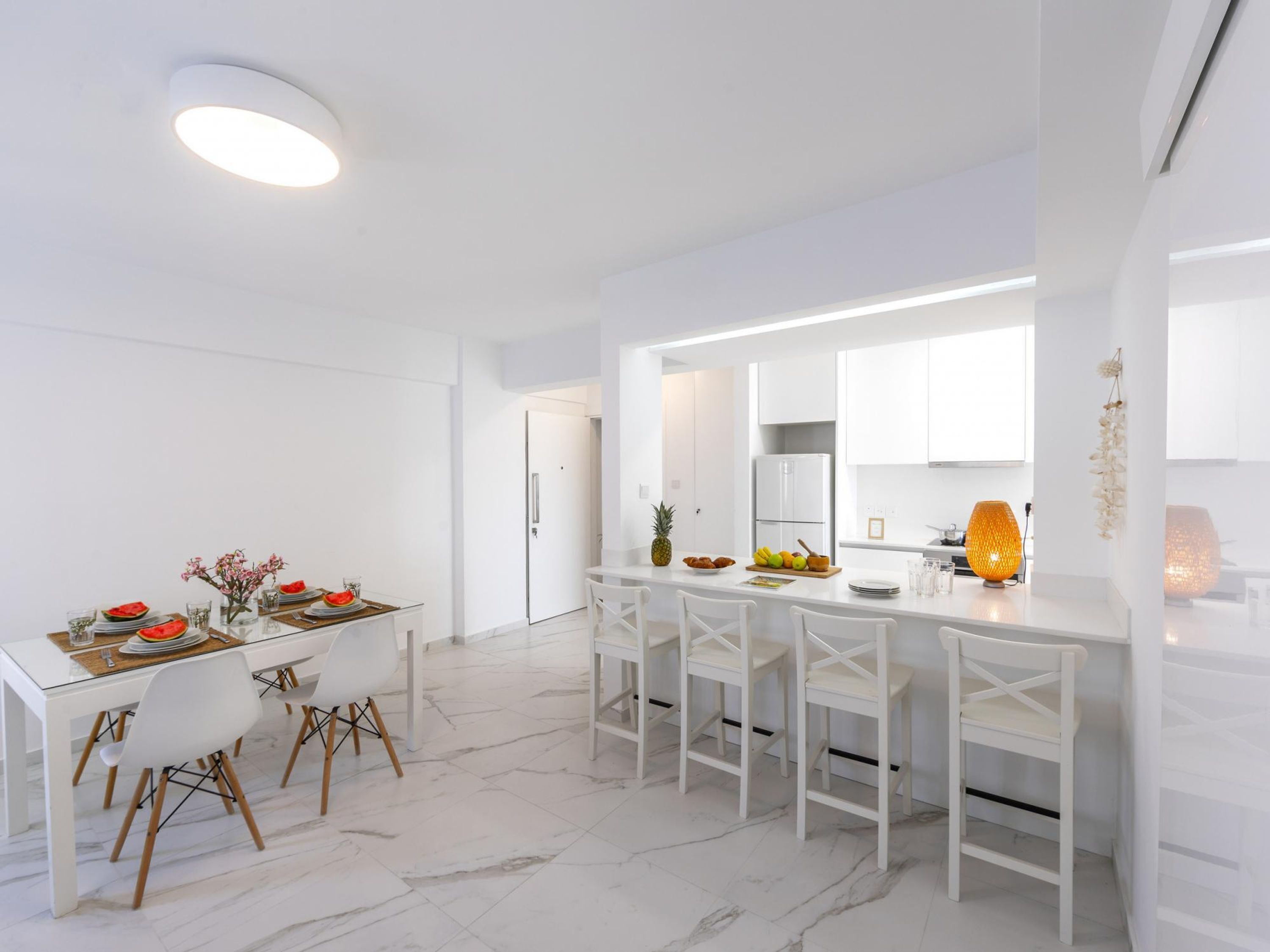 A modern kitchen with white cabinetry, a central island with seating, and a bright overhead light.