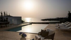 Uma área de piscina com espreguiçadeiras, um sofá e uma mesa com um vaso de flores.
